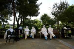Healthcare workers wearing protective suits wait during a COVID-19 testing campaign at a care home for the elderly in Barcelona. By LLUIS GENE (AFP)