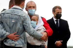 Hostage release: French President Emmanuel Macron, right, stands next to French aid worker Sophie Petronin, centre, as she is welcomed by her family on her return to France. By GONZALO FUENTES (POOL/AFP)