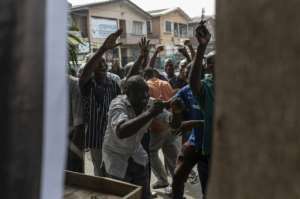 Hungry for news: Nigerians rallied around a newspaper vendor on Feb. 16 after the Independent National Electoral Commission (INEC) announced the postponement of a week of presidential elections. By STEFAN HEUNIS (AFP)