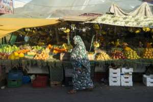 In this file photo, a woman walks past a fresh produce stand at a market in the town of Laâyoune, in the Moroccan-controlled Western Sahara.  By FADEL SENNA (AFP)