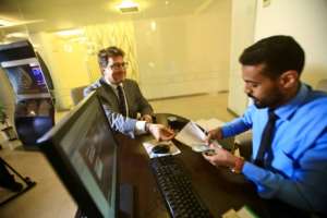Keith Hughes, public affairs officer at the US Embassy in Khartoum, opens an account at a branch of the Bank of Khartoum. By ASHRAF SHAZLY (AFP)
