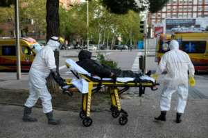 Madrid Civil Protection paramedics in full protective gear wheel a homeless man suspected of being infected with the novel coronavirus in Madrid on April 11, 2020. By OSCAR DEL POZO (AFP)
