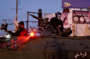 Members of Tunisia's National Guard sit atop an armoured personnel carrier to stop protesters. By FETHI BELAID (AFP)