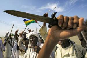 Members of the Beja ethnic group of eastern Sudan wave the flag of the Beja Congress political group as they demonstrate outside the Osman Digna port. By ASHRAF SHAZLY (AFP/File)