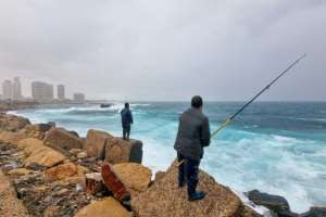 Men fish in the Mediterranean in Libya's capital Tripoli on December 13, 2021. By Mahmud Turkia (AFP)