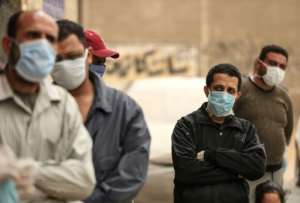 Men wait outside a centre of the non-governmental Egyptian Food Bank to receive cartons with foodstuffs in April. By Mohamed el-Shahed (AFP/File)