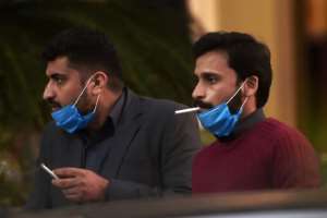 Men wearing masks smoke outside a Pakistan-based Chinese company in Islamabad. By Aamir QURESHI (AFP)