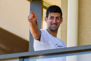 Men's world number one tennis player Novak Djokovic gestures from his hotel balcony in Adelaide, one of the locations where players have quarantined for two weeks ahead of the Australian Open tennis tournament in Melbourne. By Brenton EDWARDS (AFP)