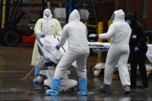 Medical personnel move a body to a refrigerated truck serving as a makeshift morgue at Brooklyn Hospital Center in New York. By Angela Weiss (AFP)