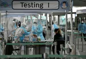 Medical staff wearing protective clothing take test samples for the COVID-19 coronavirus from a foreign passenger at a virus testing booth outside Incheon international airport near Seoul.  By Jung Yeon-je (AFP)