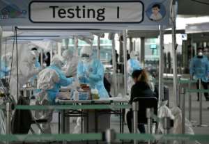 Medical staff wearing protective clothing take test samples for the COVID-19 coronavirus from a foreign passenger at a virus testing booth outside Incheon international airport near Seoul. By Jung Yeon-je (AFP)