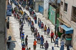 Migrant workers wait on marked areas on the ground to maintain social distancing as they queue to receive food packets in Chennai, India. By Arun SANKAR (AFP)