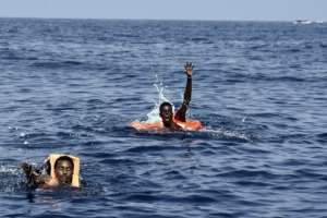 Migrants wave at members of the Proactiva Open Arms NGO as they wait to be rescued in the Mediterranean Sea off the coast of Libya on October 4, 2016