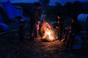 Migrants light a fire in their makeshift camp on Chios island. By LOUISA GOULIAMAKI (AFP)