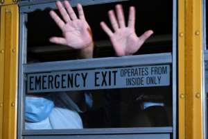 Migrants, part of a group of 76 Guatemalans deported from the United States, wave from a bus upon landing at the Air Force base in Guatemala City. By Johan ORDONEZ (AFP)
