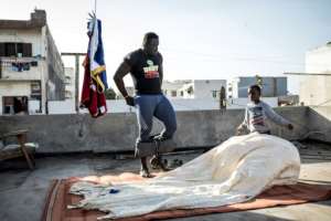 Moussa Diop training on the roof with the help of his nephew. By JOHN WESSELS (AFP)