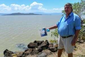 Murray Roberts, 69, holds an old photo of his sons jumping off a cliff face into the lake from the edge where he is standing that is now submerged. By TONY KARUMBA (AFP)