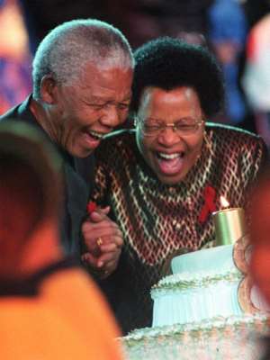 Nelson Mandela blows out a candle on his 80th birthday with his wife Graca Machel in 1998