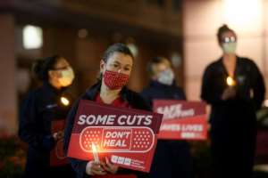 Nurses hold candles during a vigil for healthcare workers who died from Covid-19 organized by California Nurses United outside of UCLA Medical Center in Los Angeles. By Patrick T. Fallon (AFP)