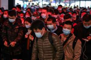 Passengers wearing face masks walk to their train at the main railway station in Wuhan, China. By Hector RETAMAL (AFP)