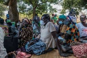 People from Lukodi gather around a radio to listen to the verdict. By Sumy Sadurni (AFP)