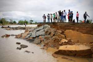 People stand near a damaged stretch of road between Beira and Chimoio, in Nhamatanda district, in central Mozambique. By ADRIEN BARBIER (AFP)