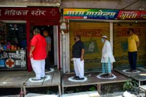 People stand on designated areas to maintain social distancing as they queue outside a medical store in Allahabad, India. By SANJAY KANOJIA (AFP)