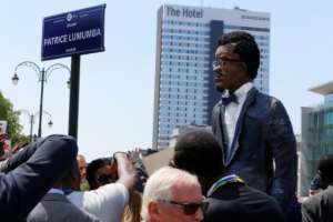 People stand next to a giant effigy of Patrice Lumumba during ceremonies in Brussels in 2018 to inaugurate a square in honor of the murdered independence hero (photo / Belga).  By NICOLAS MAETERLINCK (BELGA / AFP / File)