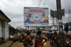 People walk past a billboard in Abidjan urging peaceful elections next month. By SIA KAMBOU (AFP)