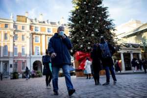 Pedestrians in face masks walk past a Christmas tree in London's Covent Garden. By Tolga Akmen (AFP)