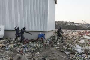 Police chase and shoot rubber bullets at two suspected looters outside a warehouse storing alcohol in Durban. By GUILLEM SARTORIO (AFP)