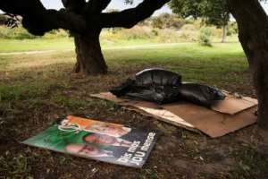 Politics and poverty: A campaign poster lies alongside the bedding of a homeless person in a Cape Town park ahead of the country's elections in May. By RODGER BOSCH (AFP)