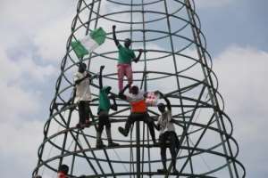 Protesters climb a telecommunication mast while carrying the Nigerian national flag. By Kola Sulaimon (AFP)
