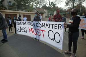 Protesters hold a sign reading