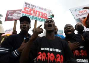 Protesters in Abuja gather in October 2021 with placards to commemorate one year after the police crackdown on Nigeria's EndSars mass demonstrations. By Kola Sulaimon (AFP/File)