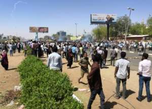Protesters take shelter from tear gas in front of the army headquarters in Khartoum, the capital of Sudan, on April 7, 2019. By - (AFP)