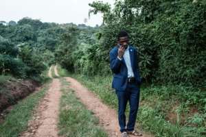 Presidential candidate Robert Kyagulanyi, also known as Bobi Wine, talks on the phone after talking to members of the media at one of his the gates of his home in Magere, Uganda, on Friday.. By Yasuyoshi CHIBA (AFP)