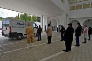 Relatives pray near an ambulance carrying the body of a Covid-19 victim before burial. By FETHI BELAID (AFP)