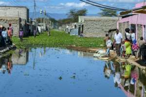 Residents of Kihoto estate on the shores of Lake Naivasha stand on elevated pavements outside their homes after the lake inundated buildings and infrastructure. By TONY KARUMBA (AFP)