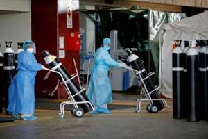 South Africa has been badly hit by coronavirus. At the Steve Biko Academic Hospital in Pretoria, health workers take oxygen tanks into a temporary ward for Covid patients. By Phill Magakoe (AFP)