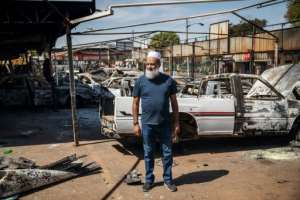 South African car dealership owner Yunus Salajee, outside the remains of the vehicles destroyed in the unrest. By Michele Spatari (AFP)