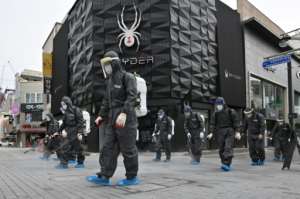 South Korean health officials from Bupyeong-gu Office wear protective gearto spray disinfectant at a shopping district in Incheon. By Jung Yeon-je (AFP)