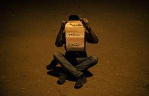 Sudanese protester Mustafa hides his face with a placard reading