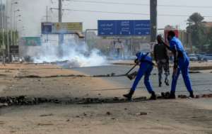 Sudanese security forces remove obstacles placed by protesters as tear gas fumes billow during a demonstration against rising prices in the capital Khartoum, on January 24. By ASHRAF SHAZLY (AFP/File)
