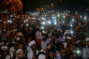 Proponents of Sudanese Islamist movements hold their phones in the air chanting slogans at a rally in front of the presidential palace on Saturday. By MOHAMED EL-SHAHED (AFP)