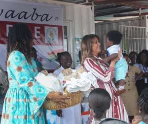 Mrs. Melania Trump holding a baby at the child welfare clinic during her visit