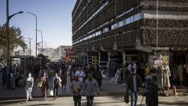 People walk past business and shops in the 4 Kilo neighbourhood of Addis Ababa on 21 March, 2024, where an urban development project is under way. - AFP - MICHELE SPATARI
