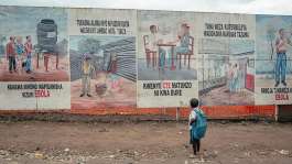 A child returning from school stops to look at Ebola awareness illustrations displayed on the signboards of the Ebola Treatment Center in Munigi on June 2, 2026. -  Jospin Mwisha, AFP