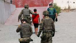 A minor from Morocco is escorted by Spanish security forces after attempting to cross into Ceuta by sea, 1 August. - REUTERS - Violeta Santos Moura