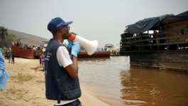 Yves Matwa, an Ebola outbreak response worker, tells passengers on Congo river ferries to brace for checks before they can enter the DR Congo capital Kinshasa.  By Sophie Douce (AFP)